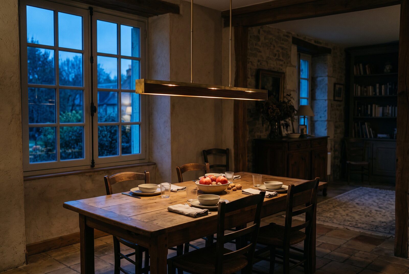 La table dressée le soir sous la suspension, la lumière tombant sur toute la longueur du plateau